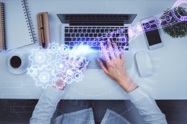 A data theme hologram drawing overlaid on a woman's hands working on a laptop.