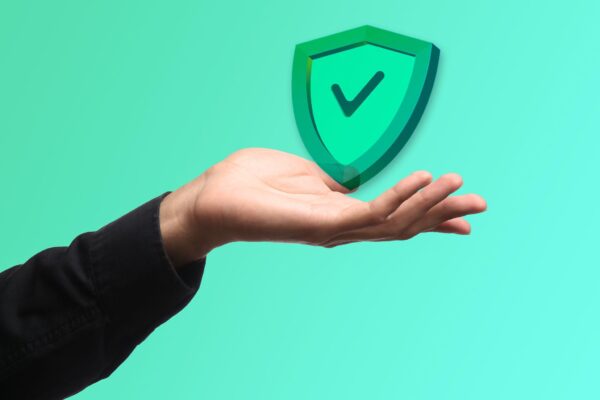 A hand holds a glowing shield icon with a checkmark, symbolizing security and trust.
